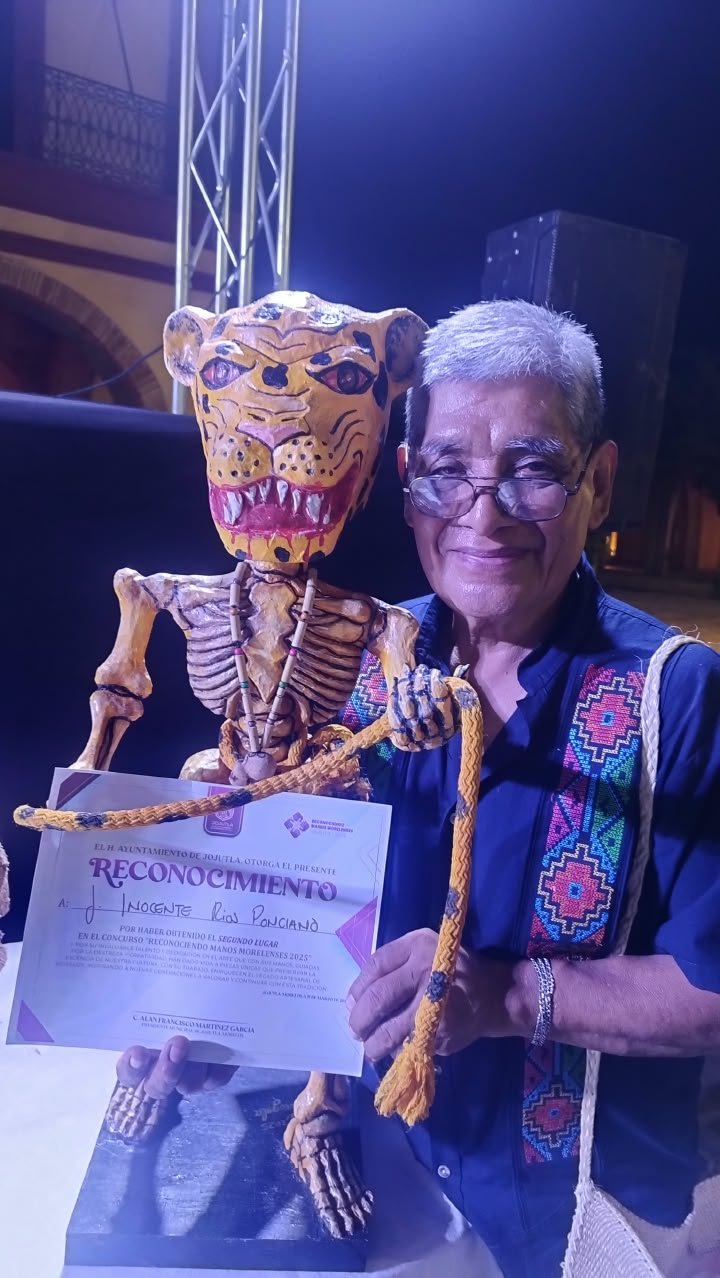 Persona junto a una figura artesanal y un reconocimiento